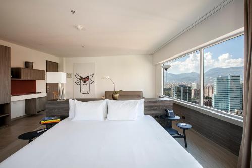 a large white bed in a room with a large window at Viaggio Medellín Grand Select in Medellín