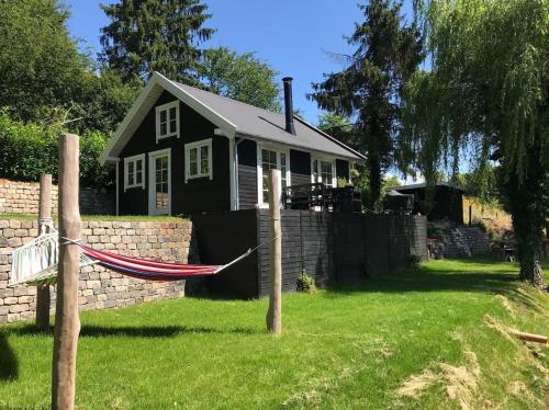 a black house with a hammock in a yard at Sommerhus i idylliske omgivelser in Veksø