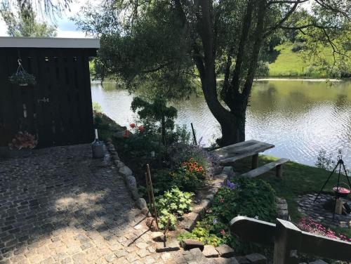 a garden with a bench and flowers next to a lake at Sommerhus i idylliske omgivelser in Veksø