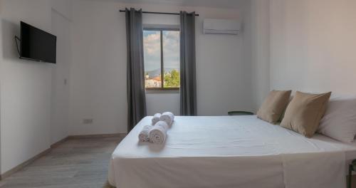 a bedroom with a large white bed with towels on it at KINGS SQUARE Holiday Apartments in Polis Chrysochous