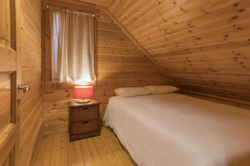 um pequeno quarto com uma cama e um candeeiro vermelho em Luna Chalets da Montanha - Serra da Estrela na Covilh