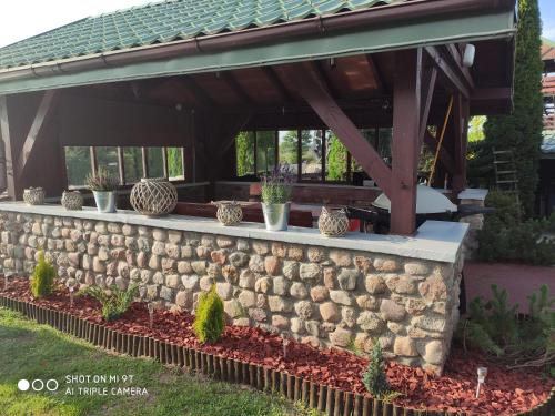 a stone retaining wall with potted plants on it at Domek nad stawem in Działdowo