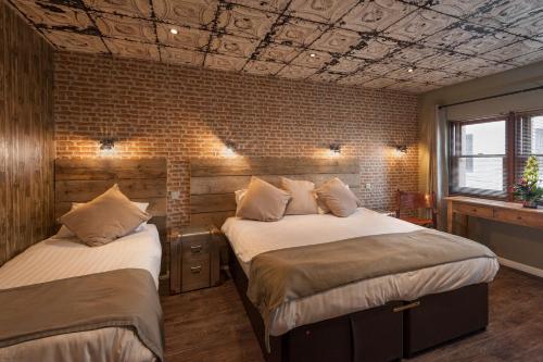 two beds in a room with a brick wall at City Retreat Edinburgh ApartHotels in Edinburgh