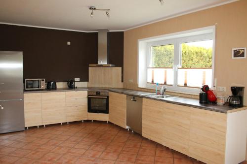 a large kitchen with wooden cabinets and a window at Ferienhaus Casa Moderna in Wiesbaum