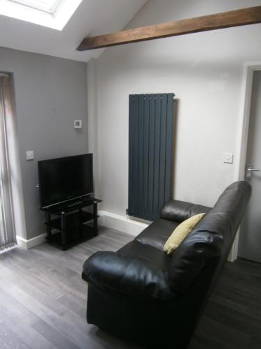 a black leather couch in a living room with a television at The Barn - Ilkeston- Close to M1-A52 Long Eaton - Nottingham - Derbyshire - 500Mbs WiFi! in Ilkeston