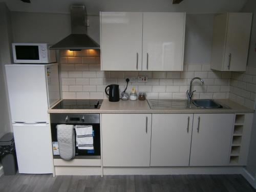 Una cocina con gabinetes blancos, un fregadero y una estufa. en The Barn - Ilkeston - 1 Bedroom Flat, 2 Beds, Close to M1-A52 Long Eaton - Nottingham - Derby - Derbyshire - 400Mbs WiFi Free Parking!, en Ilkeston