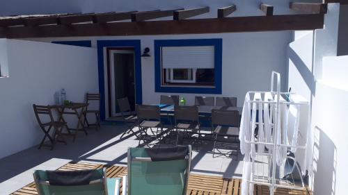 a patio with chairs and a table and a blue wall at Casa Férias Melides in Melides