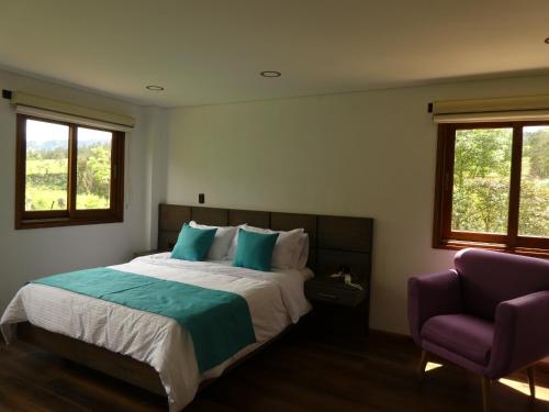 a bedroom with a bed and a purple chair at Hotel Campestre El Portón de Los Jeroglíficos in Ramiriquí