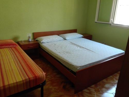 een slaapkamer met een bed, 2 tafels en een raam bij Villa Simone in Pachino