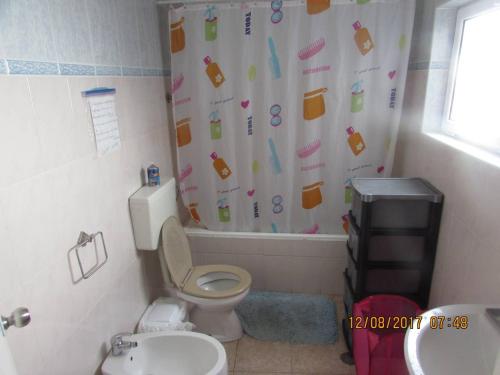 a bathroom with a toilet and a shower curtain at Casa Benarus in Angra do Heroísmo