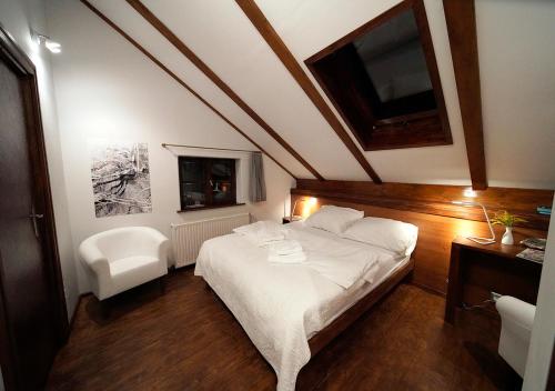 a bedroom with a large white bed and a chair at Ojców Bazar Lwowski in Ojców