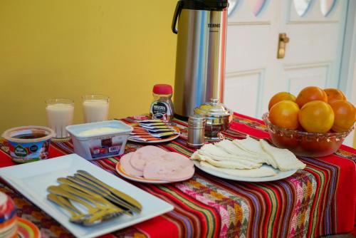 a table with plates of food and a bowl of oranges at Holidays Hostel Arequipa in Arequipa