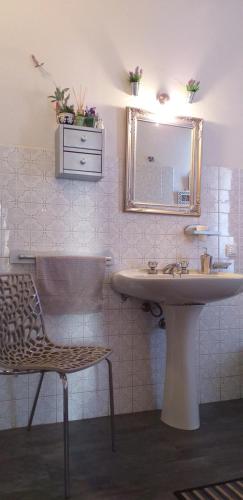 a bathroom with a sink and a mirror and a chair at Le Finestre di San Michele in Castiglion Fiorentino