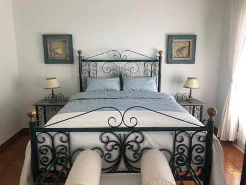 a black bed in a room with two lamps at Casa da Oliveira in Vila Nova de Milfontes