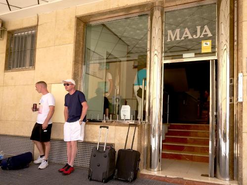 two men standing outside of a building with luggage at Apartamentos Maja in Benidorm