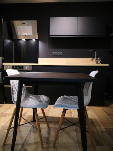 une cuisine avec un bureau noir et deux chaises dans l'établissement Studio moderne,parking,piscine,tennis,terrasse., à Aix-les-Bains