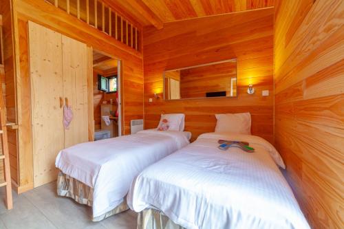 two beds in a room with wooden walls at Le Moulin in Martres-Tolosane