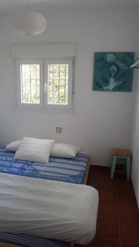 1 dormitorio con 2 camas y 2 ventanas en Chalet la barrosa a 800 mts playa, en Chiclana de la Frontera