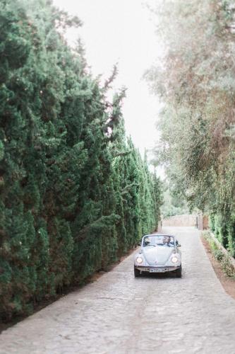 an old car driving down a road next to trees at Casal Santa Eulalia in Can Picafort