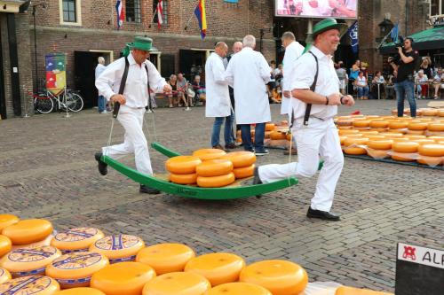 two men in green hats pulling a boat of cheese at Grand Hotel Alkmaar in Alkmaar