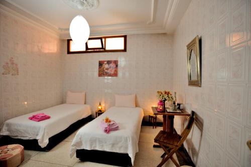 a room with two beds and a table with flowers at LHOSTEL à Casablanca in Casablanca
