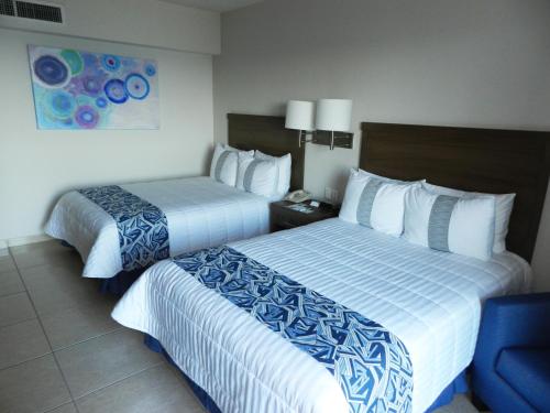 a hotel room with two beds and a chair at Hotel Villa Florida Veracruz in Veracruz