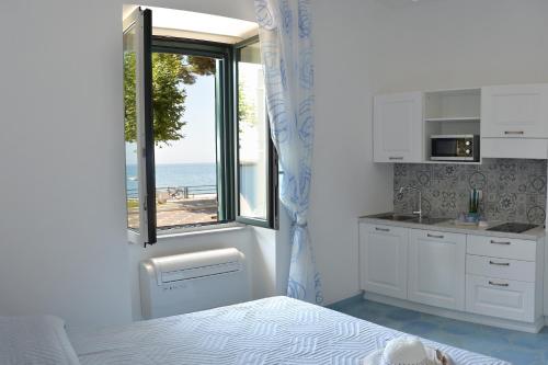 a kitchen with a bed and a window with a view of the ocean at Una Finestra sul Mare in Maiori