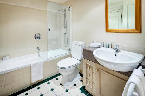 une salle de bain avec un lavabo, des toilettes et une douche dans l'établissement Adina Heritage Christchurch, à Christchurch