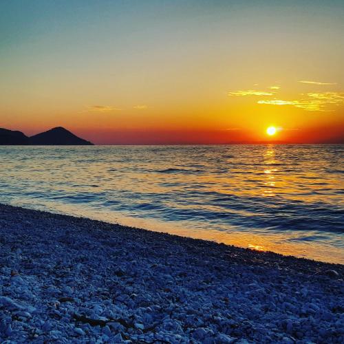 a sunset on the beach with the sun setting at Loft Vista Mare Elba in Portoferraio