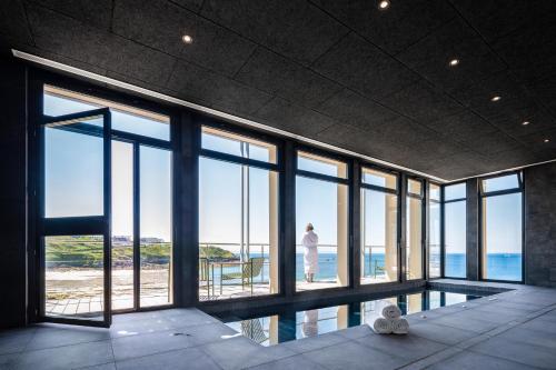 une personne debout dans une pièce donnant sur l'océan dans l'établissement Sainte-Barbe Hotel & Spa Le Conquet - MGallery Collection, au Conquet