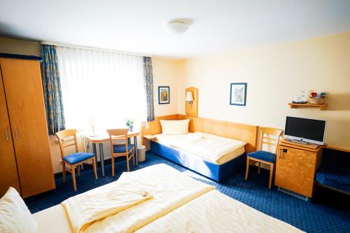 a hotel room with two beds and a table at Hotel Sauer Garni in Neu Isenburg