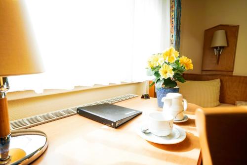 a table with two cups and a laptop on it at Hotel Sauer Garni in Neu Isenburg