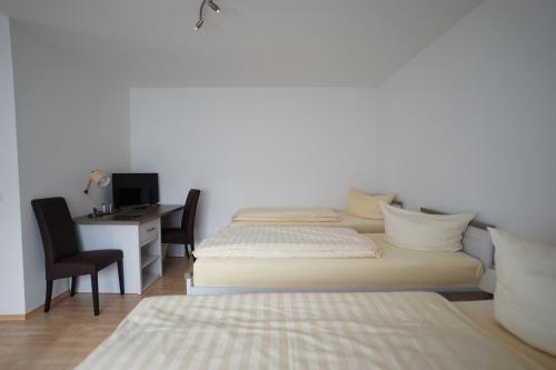 a bedroom with two beds and a desk with a computer at Hotel Sauer Garni in Neu Isenburg