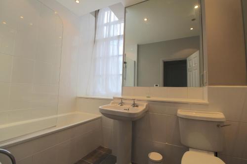 uma casa de banho com um lavatório, um WC e um espelho. em Royal Mile Mansions by Edinburgh City Apartments em Edimburgo