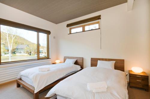 two beds in a bedroom with a window at Hana & Jo in Kutchan