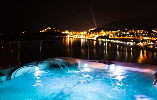 a hot tub with a view of the water at night at Hotel Ponta Nova in Budva