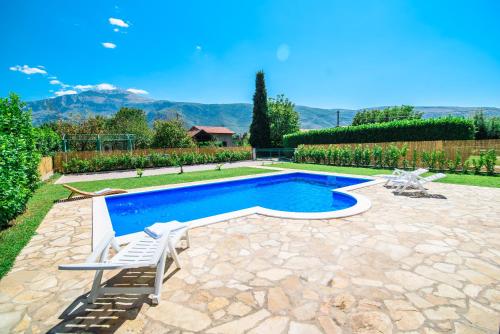 a swimming pool with two lounge chairs next to a house at Villa Mirna in Mostar