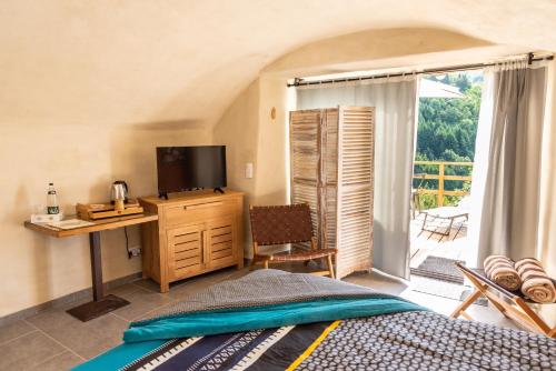 a bedroom with a bed and a television and a balcony at La Calade Chambres d'Hôtes & Espace Bien-Etre in Chirols