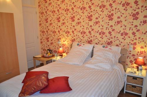 a bedroom with a bed with white sheets and red pillows at La Gentilhommière du Château de Ragnies in Ragnies