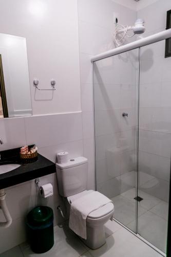 a bathroom with a toilet and a glass shower at Chapada Park Pousada e Restaurante in Chapada dos Guimarães