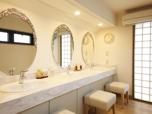 uma casa de banho com dois lavatórios e dois espelhos em Bishoku no Kakurega Provence em Shima