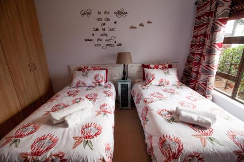 two twin beds in a room with writing on the wall at Froggy Bay is the best all the way! in Simonʼs Town