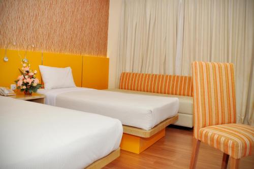 a hotel room with two beds and a chair at Pandanaran Hotel in Semarang