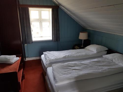 two beds in a blue room with a window at Guesthouse Gamli Bær in Húsafell