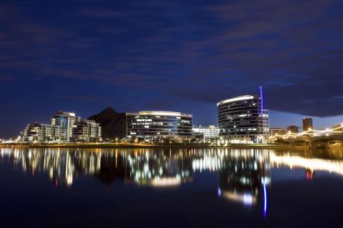 a city skyline at night with its lights reflecting in the water at Tempe Mission Palms, a Destination by Hyatt Hotel in Tempe