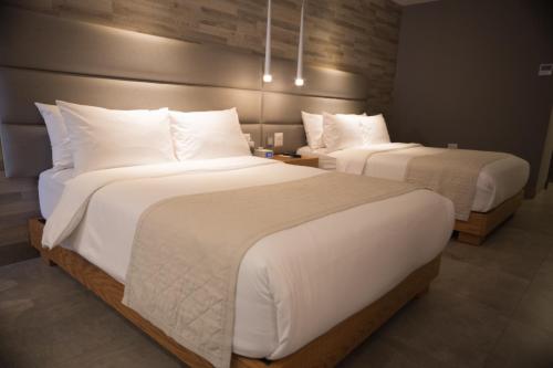 two beds in a hotel room with white pillows at Oro Verde Manta in Manta