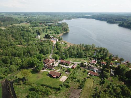 eine Luftansicht eines Hauses neben einem See in der Unterkunft Folwark Tumiany Pokoje & Restauracja in Tumiany