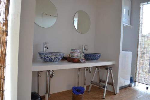 a bathroom counter with two sinks and two mirrors at Guesthouse Muga in Hikone