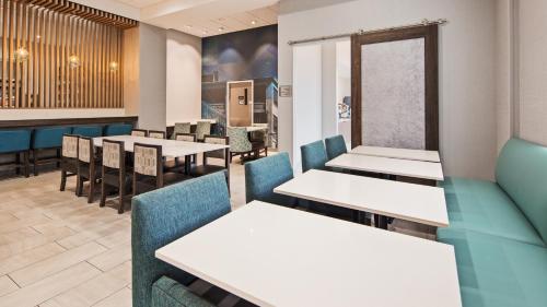 a dining room with white tables and blue chairs at Best Western Plus Wilkes Barre-Scranton Airport Hotel in Pittston