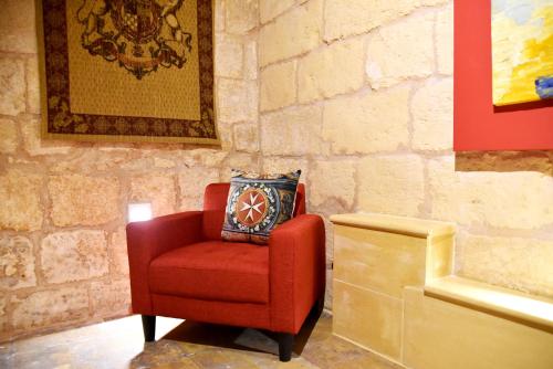 a red chair with a pillow on a wall at The Lodge in Cospicua
